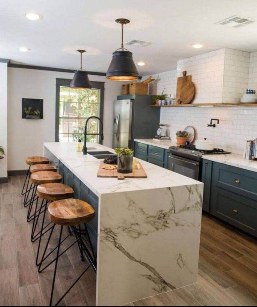 Kitchen with marble seated island and chairs, blue cabinets, and brown wood floors